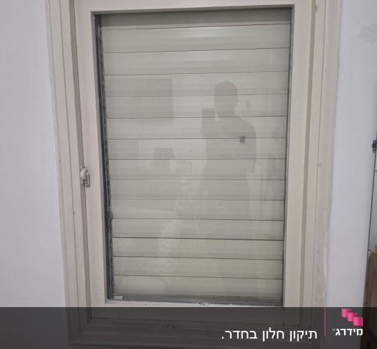 חלון עם תריס סגור על קיר לבן